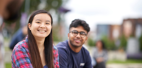 male and female students sitting outside